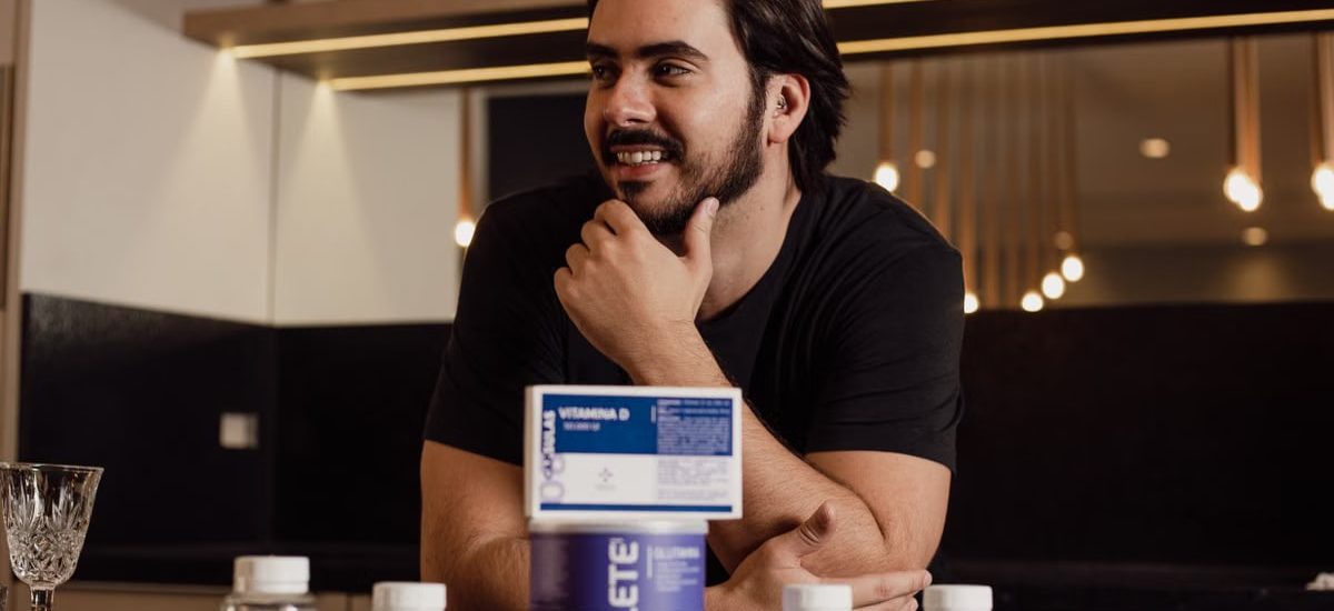 A man enjoying wellbeing surrounded by supplement bottles in a modern kitchen.