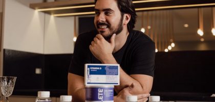 A man enjoying wellbeing surrounded by supplement bottles in a modern kitchen.