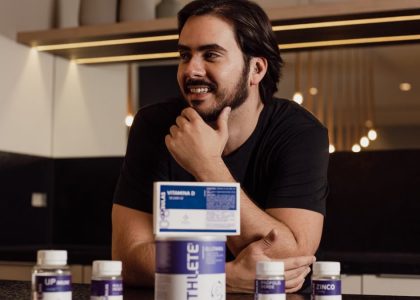 A man enjoying wellbeing surrounded by supplement bottles in a modern kitchen.