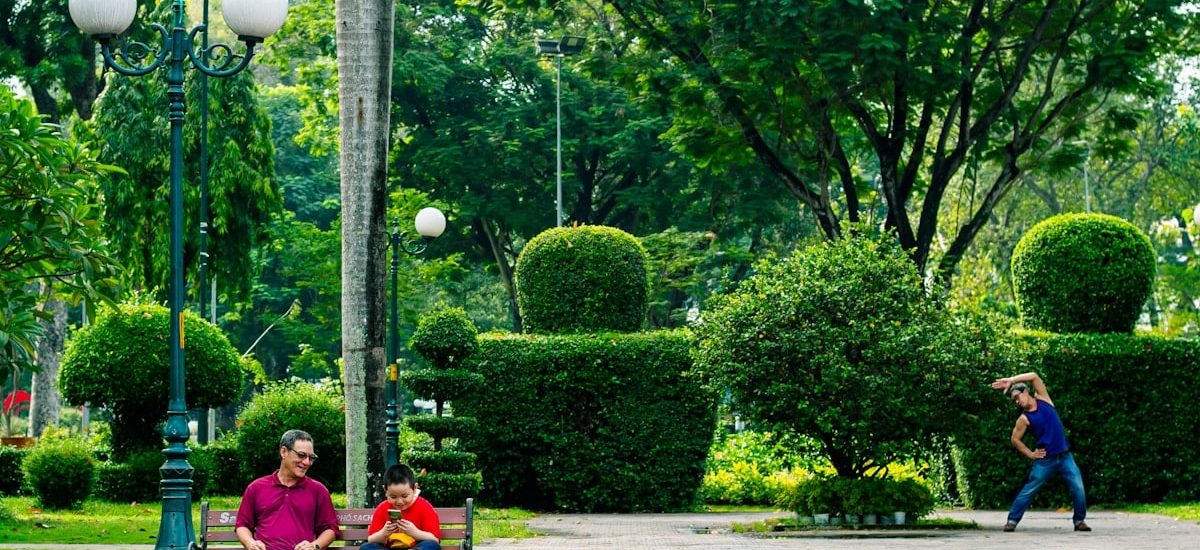 People relaxing in a lush green park with topiaries.