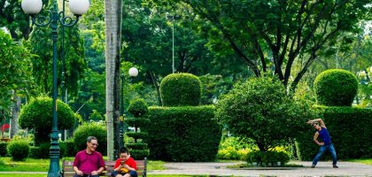 People relaxing in a lush green park with topiaries.