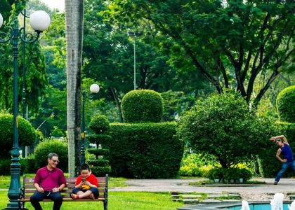 People relaxing in a lush green park with topiaries.