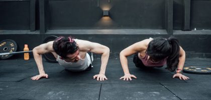 Two adults doing push-ups in an indoor gym setting in Mexico City, promoting a fit and healthy lifestyle.
