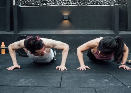 Two adults doing push-ups in an indoor gym setting in Mexico City, promoting a fit and healthy lifestyle.
